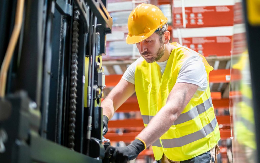Side view of a worker working on forklift What Factors Affect a Forklift's Lifting Capacity? HTX Material Handling, Houston