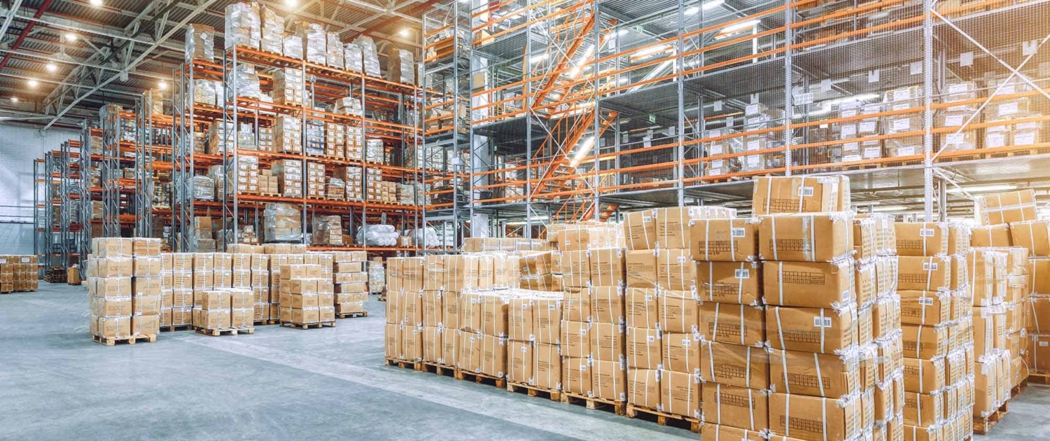 Large Industrial Warehouse With High Racks. In The Foreground Are A Lot Of Cardboard Boxes