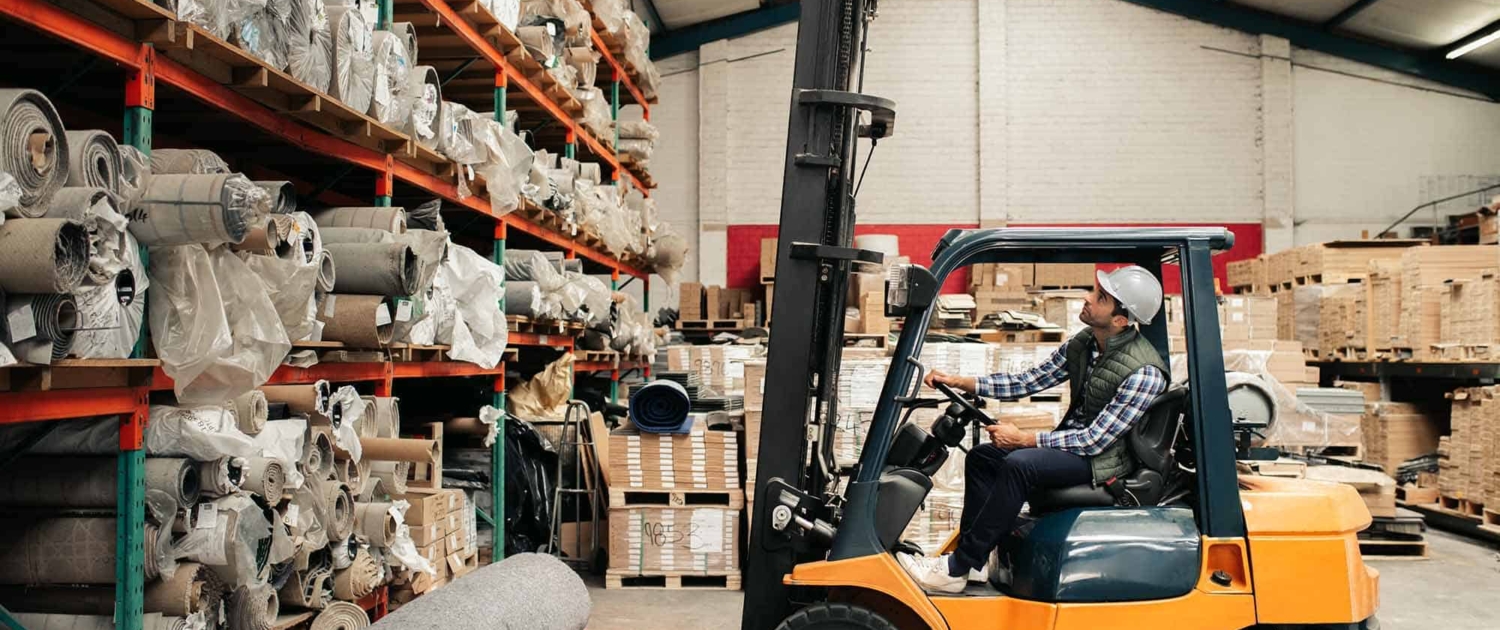 Forklift Driver Carefully Moving Stock Around A Large Warehouse
