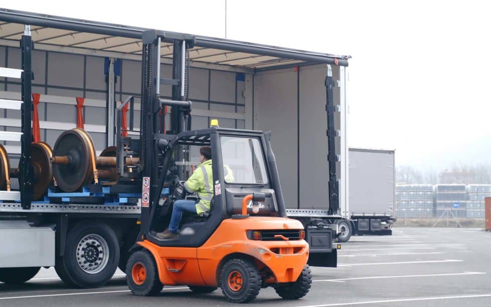 Orange Forklif Loading Equipment Into Truck 980x613
